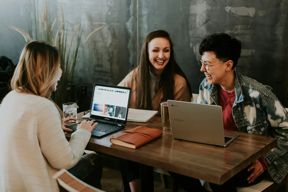 Tres jóvenes que parecen estar trabajando en equipo en sus ordenadores.